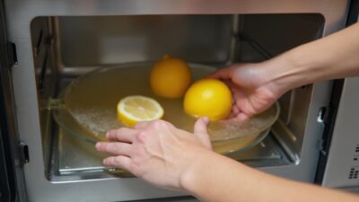 Manos colocando limones dentro de un horno microondas